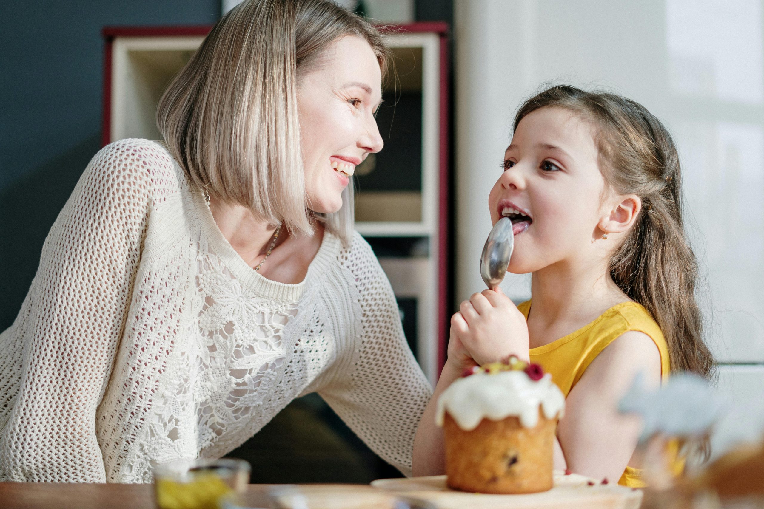 A joyful moment of mother and daughter baking and decorating an Easter cake at home.